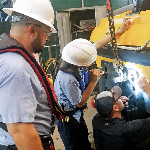 Technical Services apprentice with Team Members inspecting an attraction ride.