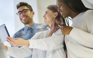 Grupo de três funcionários, sorrindo e colaborando no trabalho