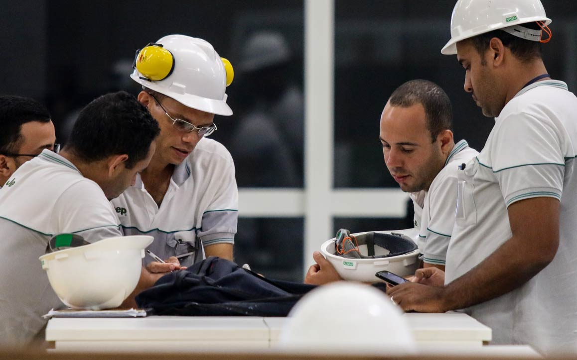 Grupo de trabalhadores com capacete de segurança envolvidos na resolução colaborativa de problemas