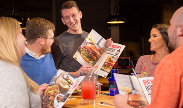 Smiling Chili’s Server interacting with smiling Guests at their table