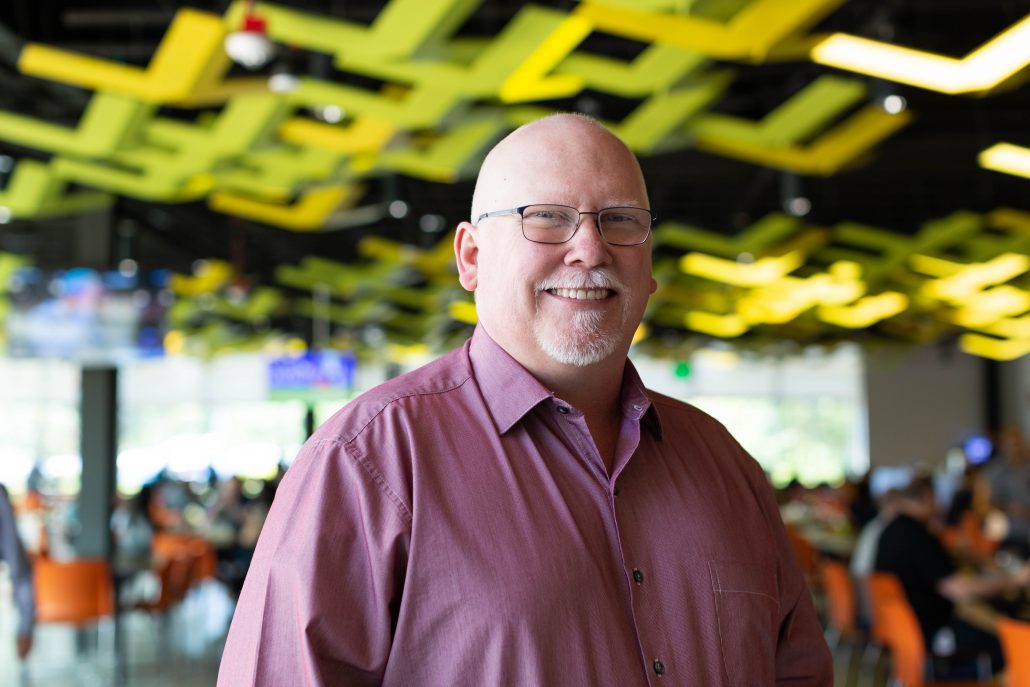 Man in ping button down shirt smiling