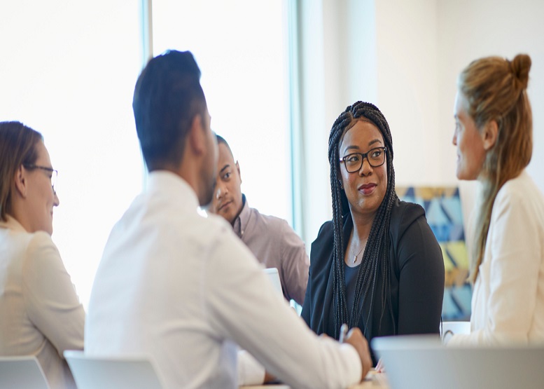 Four coworkers smiling as the hold conversation in office
