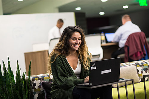 Actuarial Woman sitting on a couch and working at laptop