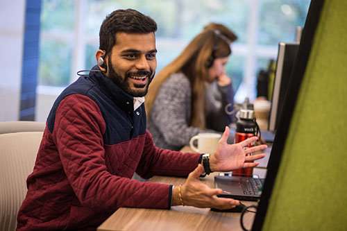 Human Resources Rotational Program Man sitting at a computer and smiling out at camera