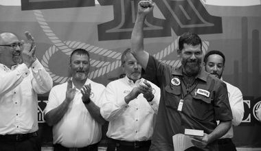 Image of a a Reyes Holdings team member celebrating his award with a group of leaders clapping in the background.