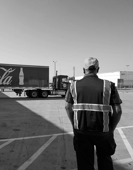 An image of a Reyes Holdings team members looking at an 18-wheeler Reyes Coca-Cola truck.