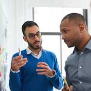 Three people discussing post-it notes on a whiteboard