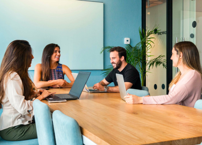 People sitting at a table with laptops and smiling