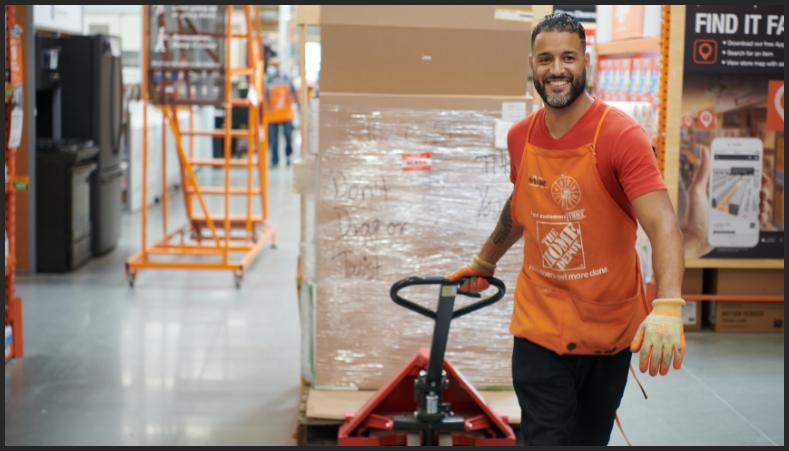 A Night Replenishment Manager smiles while pulling a pallet jack through the store.