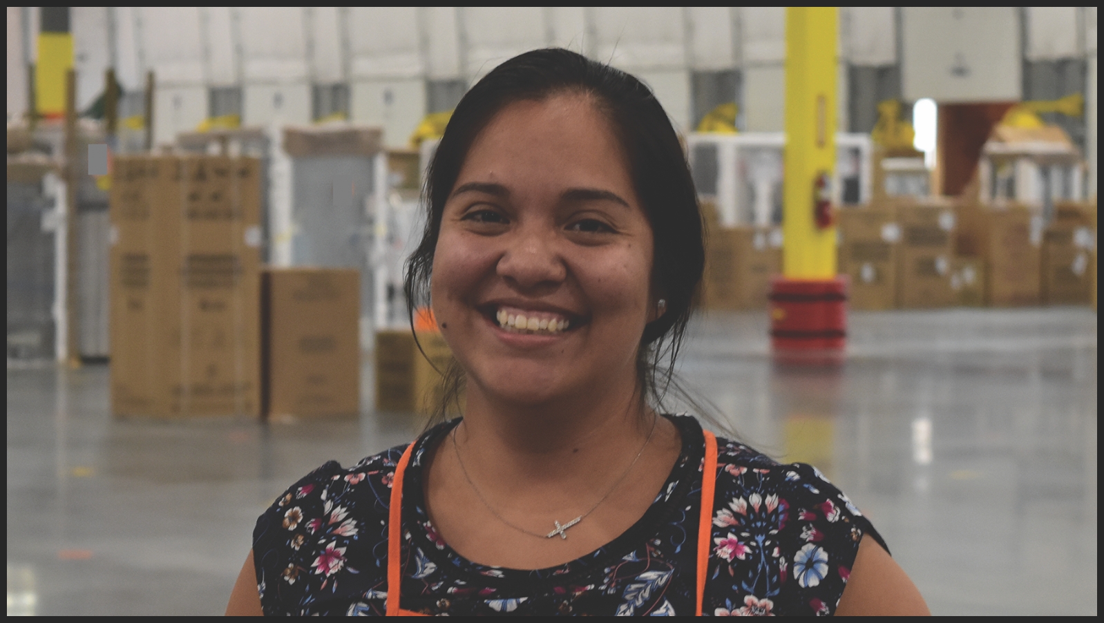 An Area Supervisor smiles into the camera inside a distribution center.