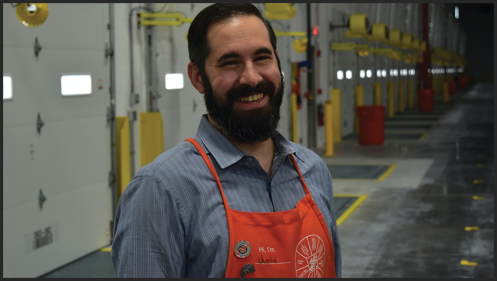 A Market Delivery Operations Manager smiles into the camera inside a distribution center.