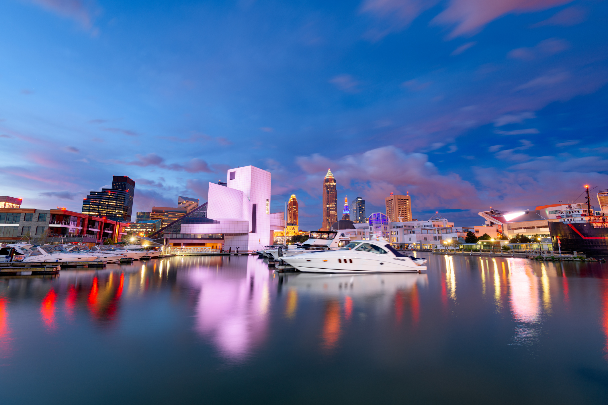 Boats docked at a marina with the Cleveland skyline at sunset.