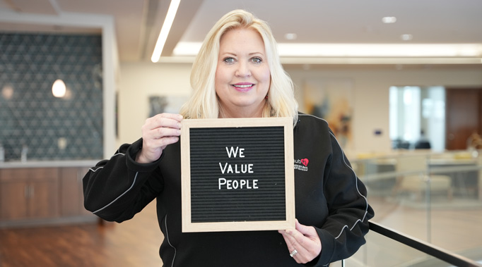 Woman holding sign saying We Value People