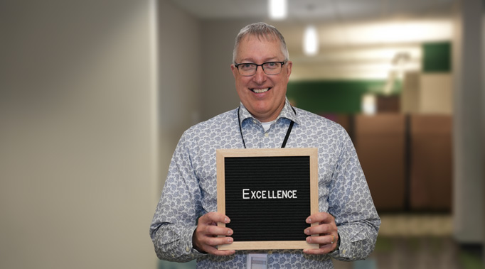 Man holding sign saying Excellence