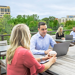 305×305 our family of biz new Man working on laptop outside of office as he speaks to a women.