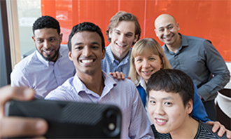 diverse-perspectives Diverse group of coworkers huddle to take a picture.
