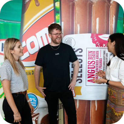 A group of people standing in front of a wall of photos of Kraft Heinz brand products.