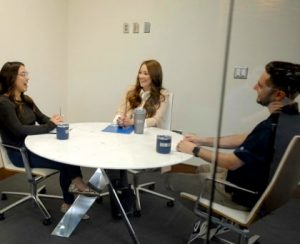 Three CNH Legal & Compliance employees sit around a table and work together.