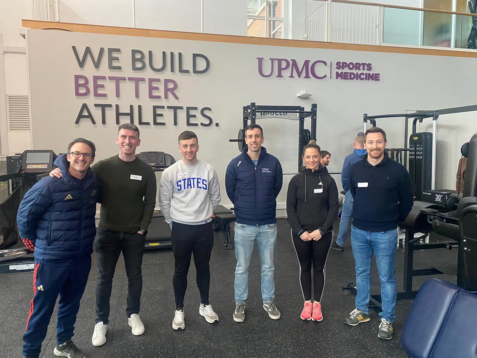 Group of colleagues stands in a sports facility in UPMC Ireland location.