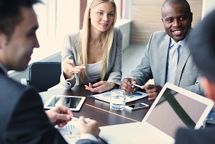 Men and women seated around a conference table discussing business.