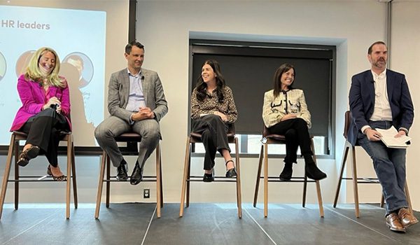 Group photo of Ann sitting on a stage and others participating in a panel discussion.
