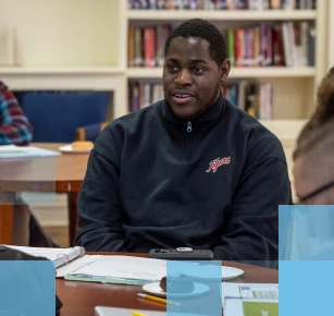 Male African American high school student sitting at a table in a library
