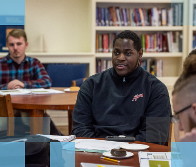 Male African American high school student sitting at a table in a library