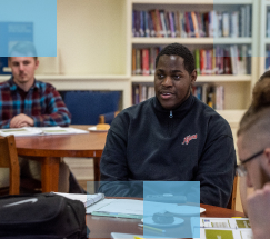 Male African American high school student sitting at a table in a library