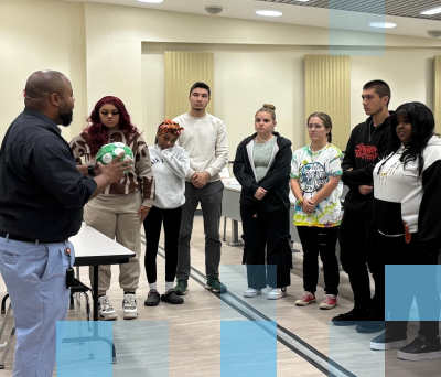 A male high school teacher leading a diverse class of high school students