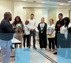A male high school teacher leading a diverse class of high school students