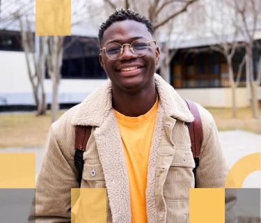 Smiling male African American high school student in front of a high school