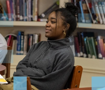 A female African American student sitting at a table in a library