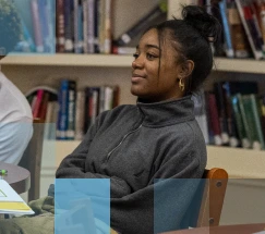 A female African American student sitting at a table in a library