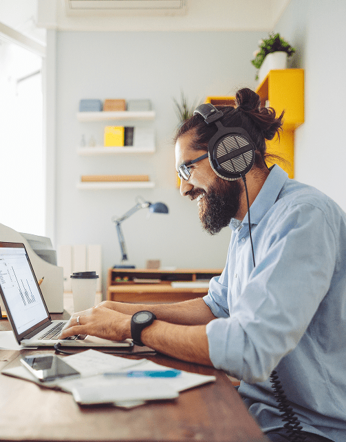 Smiling male professional wearing headphones and working at a laptop computer