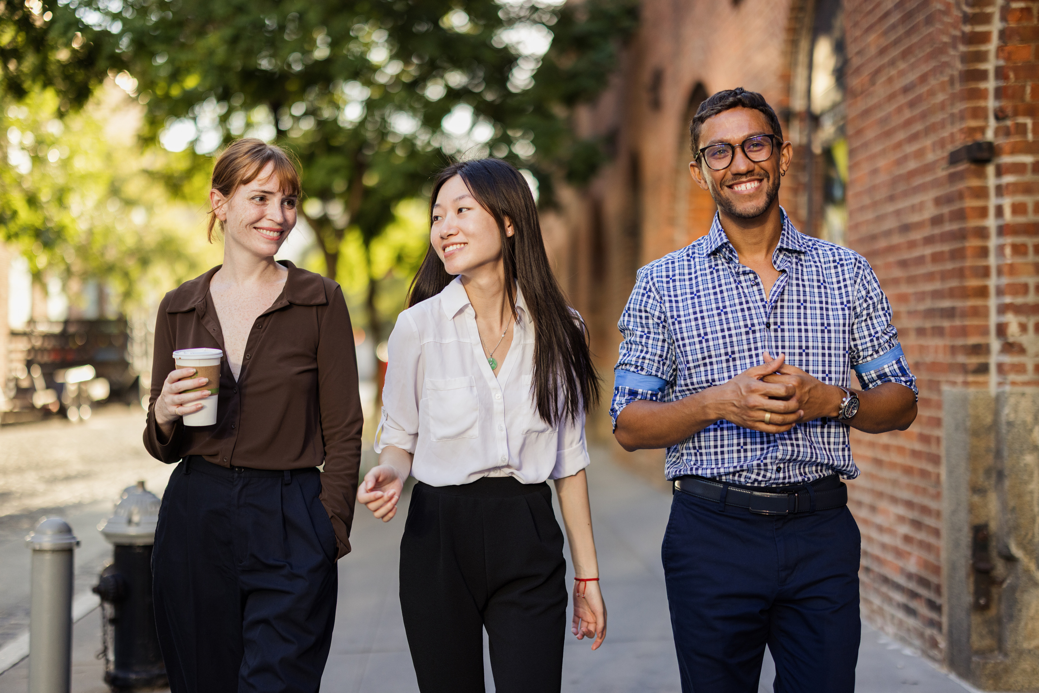 Three professionals walking together in an urban setting, appearing confident and engaged as they head to work—reflecting a modern, collaborative workplace culture.