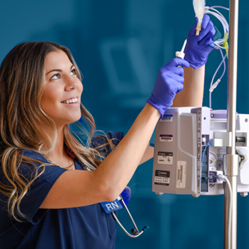 A smiling female nurse resident working on a patient's IV medication