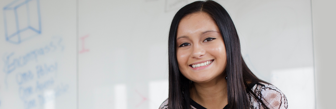 Smiling female Allstate tech employee, leaning on chair and looking at the camera.