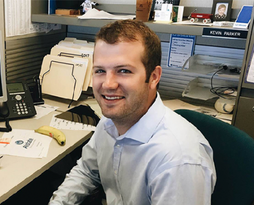 Smiling male Allstate employee working at his desk.