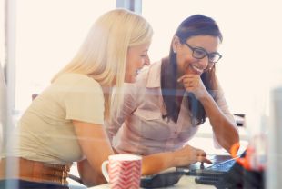 two women seated at a desk, collaborating on work