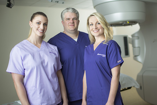 Three nurses standing in front MRI machine