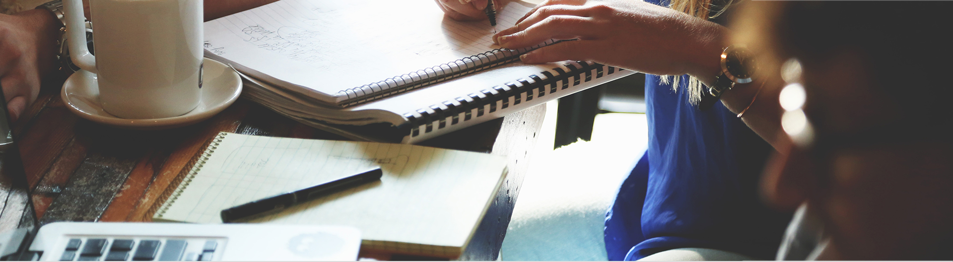 Girl writing notes on her study table with coffee mug