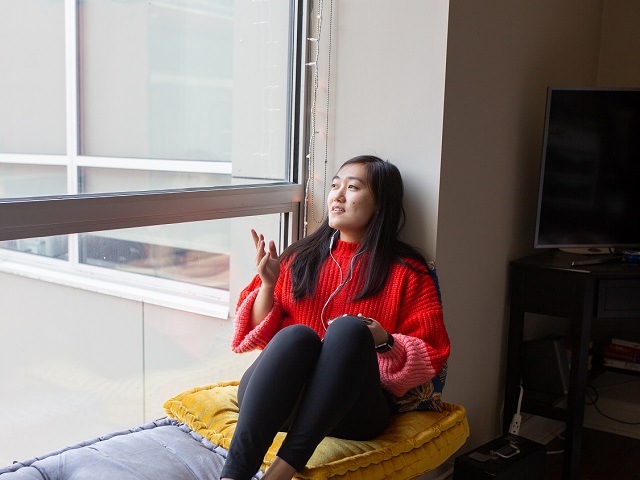 Featured Image. Devon on her phone by the window.